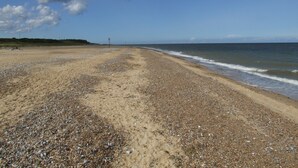 A beach with pebbles and sand, a clear sky, and a distant horizon. - Charming Woodland Lodge 2 person 1 bedroom (Great Yarmouth)