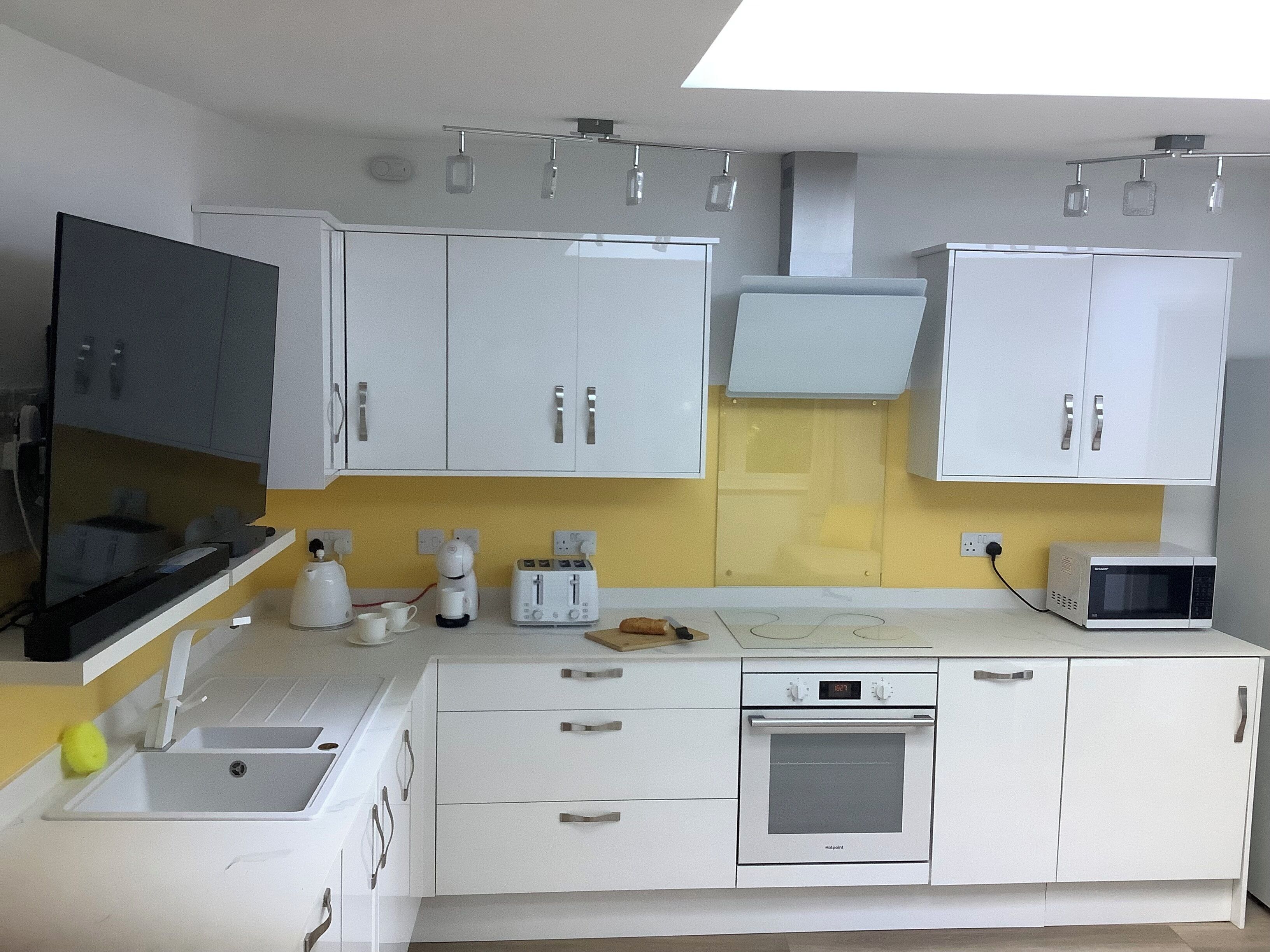 A modern kitchen with white cabinets, a built-in microwave, a toaster, and a sink.