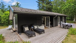 Une cabane dotée d’une terrasse, de sièges extérieurs et d’une table.