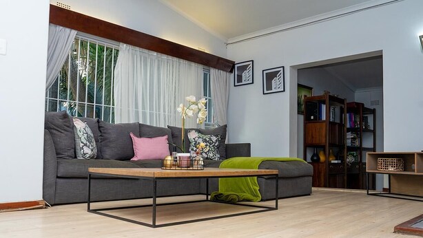 Un salon moderne avec un canapé gris, une table basse en bois et une bibliothèque.