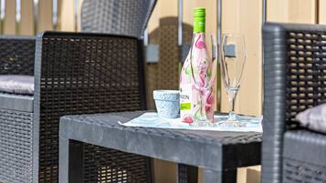 Une chaise en osier, une table avec une bouteille et un verre, et une petite tasse bleue et blanche.