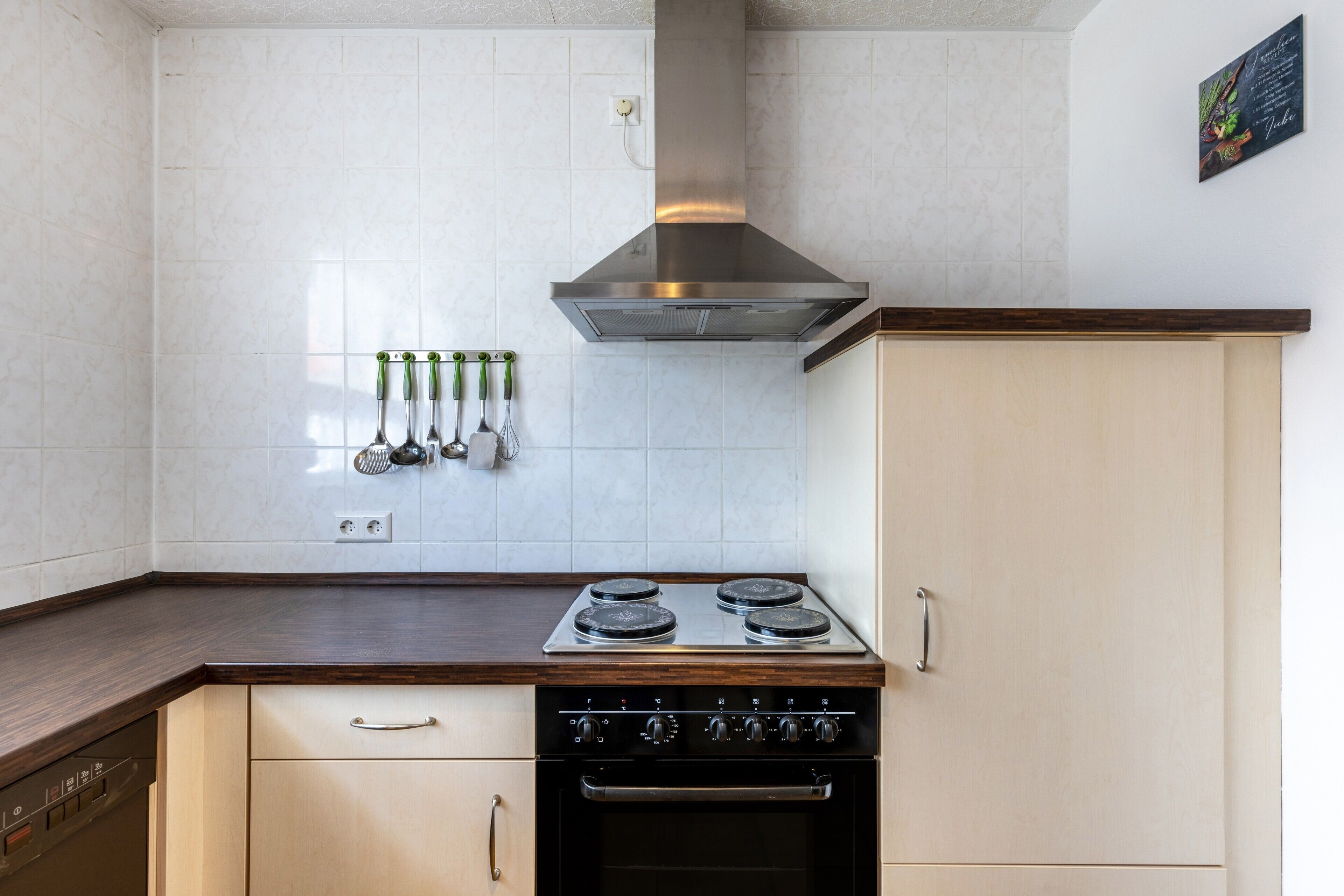 Uma cozinha com fogão, forno e utensílios fixados na parede.