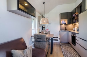 Una cocina compacta con comedor, horno empotrado y una lámpara colgante.