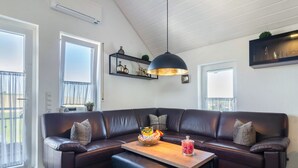 Ein modernes Wohnzimmer mit einem dunkelbraunen Ledersofa, einem Couchtisch aus Holz und einer Pendelleuchte.