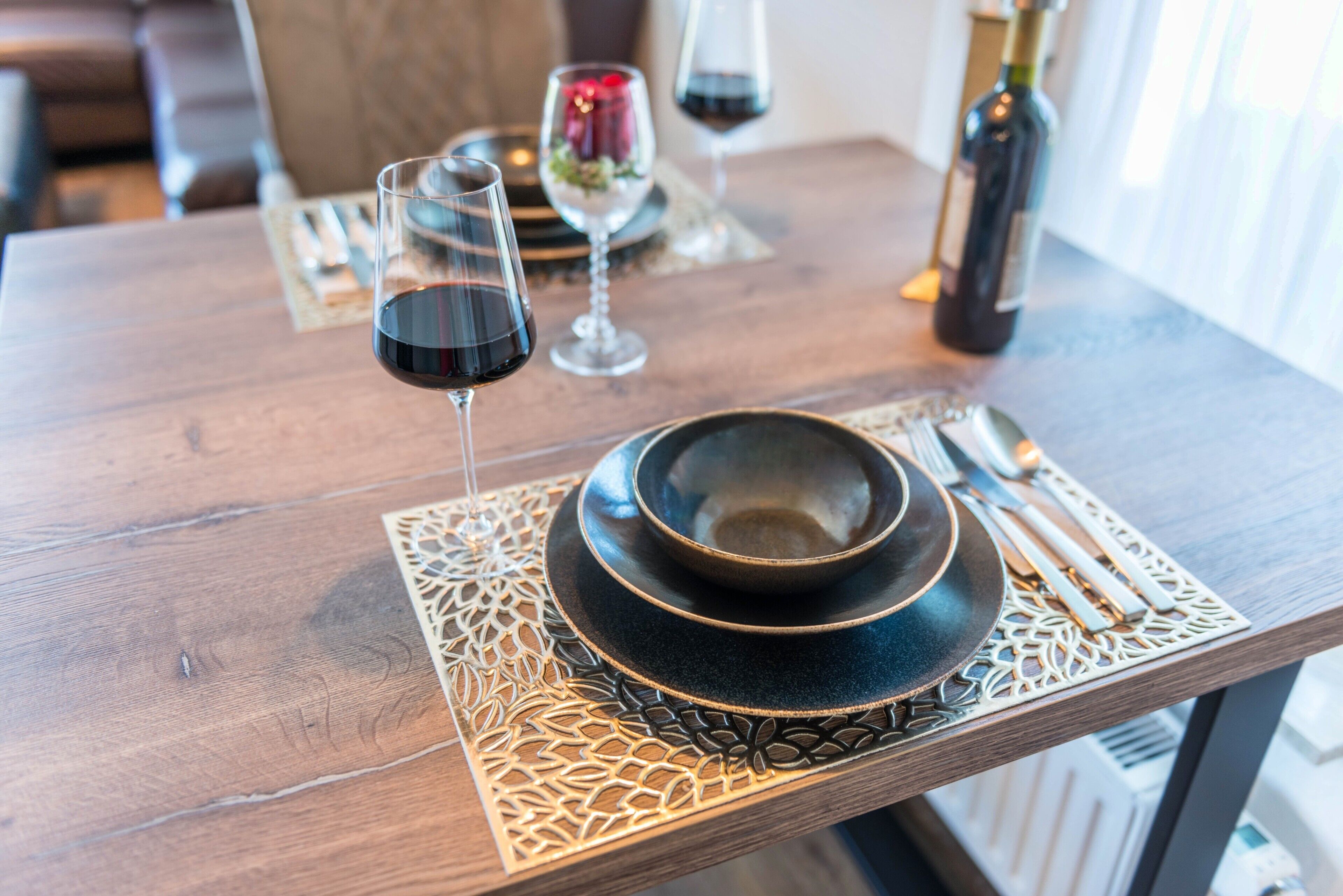 Une table à manger avec un saladier, des verres à vin et des couverts.