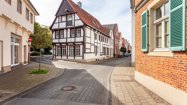 Une rue bordée de maisons traditionnelles à colombages, une route dégagée et un trottoir.