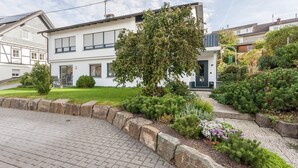 Una casa moderna de dos plantas con un jardín cuidado, entrada pavimentada y el número 39 visible en la puerta.