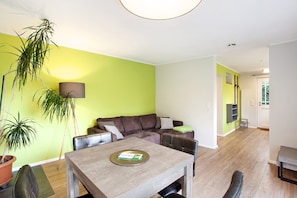 Un salon avec un canapé, une table à manger et une plante en pot.