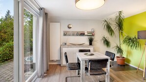 Una cocina moderna con comedor, ventanas amplias y plantas en macetas.