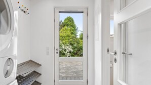 A clean, modern bathroom with a shower, a toilet, and a sink. There is a window with a view of trees and a clear sky.