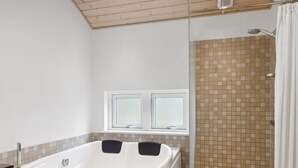 A modern bathroom with a freestanding bathtub, a glass shower enclosure, and a window above the bathtub.
