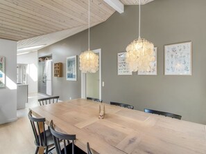 A dining area with a large wooden table, black chairs, and two hanging light fixtures.