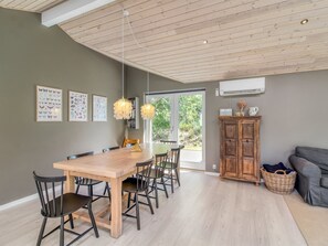 Een eetruimte met een houten tafel en stoelen, een hanglamp en uitzicht op het omliggende landschap.