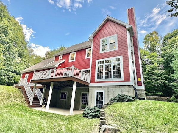 Une maison à deux étages avec un balcon, une cheminée et des fondations en pierre.