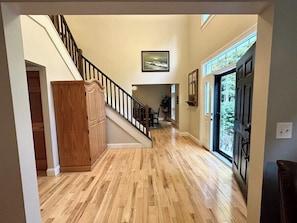 Un escalier en bois mène à une salle à manger qui offre une vue sur les arbres.
