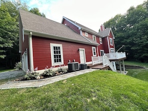Une maison rouge à deux étages, dotée d’un porche à l’avant et d’une petite terrasse.