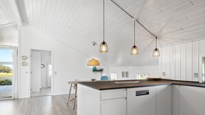 A modern kitchen with white cabinetry, a wooden island, pendant lights, and a view of the outdoors. - "Blaguna" - 600m from the sea by Interhome (Thisted)