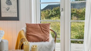 A cozy room with a wicker chair, a glass table with candles, and a view of greenery outside. - "Blaguna" - 600m from the sea by Interhome (Thisted)