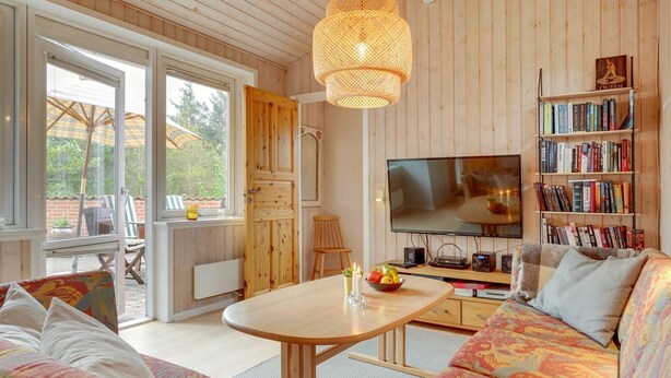 A cozy living room with a large TV, a bookshelf, and a dining area with a table and chairs.