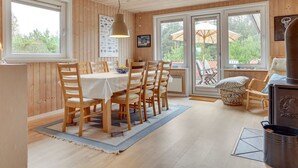 A wooden-paneled room with a dining table, chairs, and a large window.