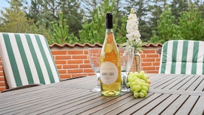 A table with a bottle of white wine, a glass, and a bunch of green grapes.