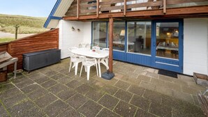 Un patio con mesa y sillas, una parrilla y una terraza de madera.