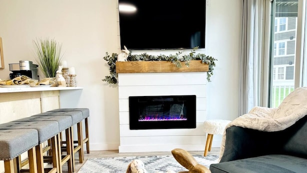 A living room with a fireplace, a sofa, a coffee table with decorative items, and a TV mounted above the fireplace.