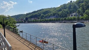 Une rivière avec des bateaux, un pont et des bâtiments sur une colline.