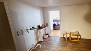 Un couloir avec un porte-manteau, une petite table avec une chaise et une porte donnant sur une autre pièce.