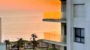 Un edificio moderno con varios balcones con vistas a una playa.