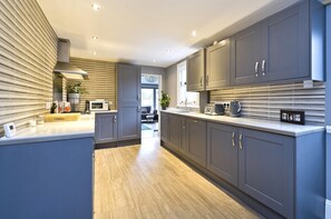A modern kitchen with grey cabinets, a wooden floor, and a microwave.