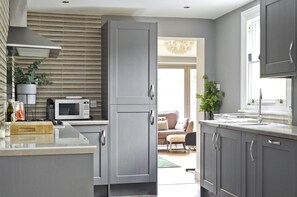 A modern kitchen with grey cabinetry, a microwave, and a sink.