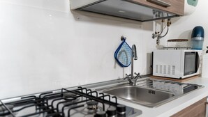 A modern kitchen with a gas stove, stainless steel sink, and a microwave. - Vico Santo Spirito di Palazzo 34 (Naples)