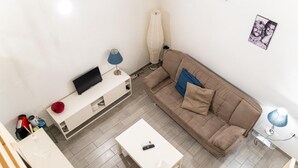 A modern living room with a sofa, a coffee table, a TV on a stand, and a lamp. - Vico Santo Spirito di Palazzo 34 (Naples)