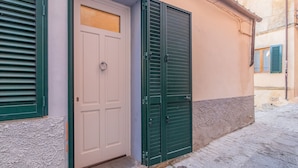Un bâtiment avec une porte blanche, des volets verts et une façade à motifs.