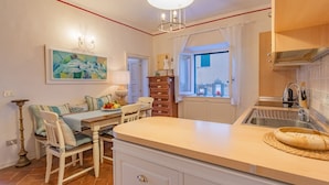 Une cuisine dotée d’un îlot central, d’un coin repas avec une table et des chaises, d’un meuble en bois et d’une fenêtre offrant une vue agréable.