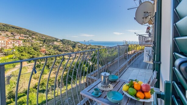 Un balcon avec une table dressée et une vue sur une ville côtière.