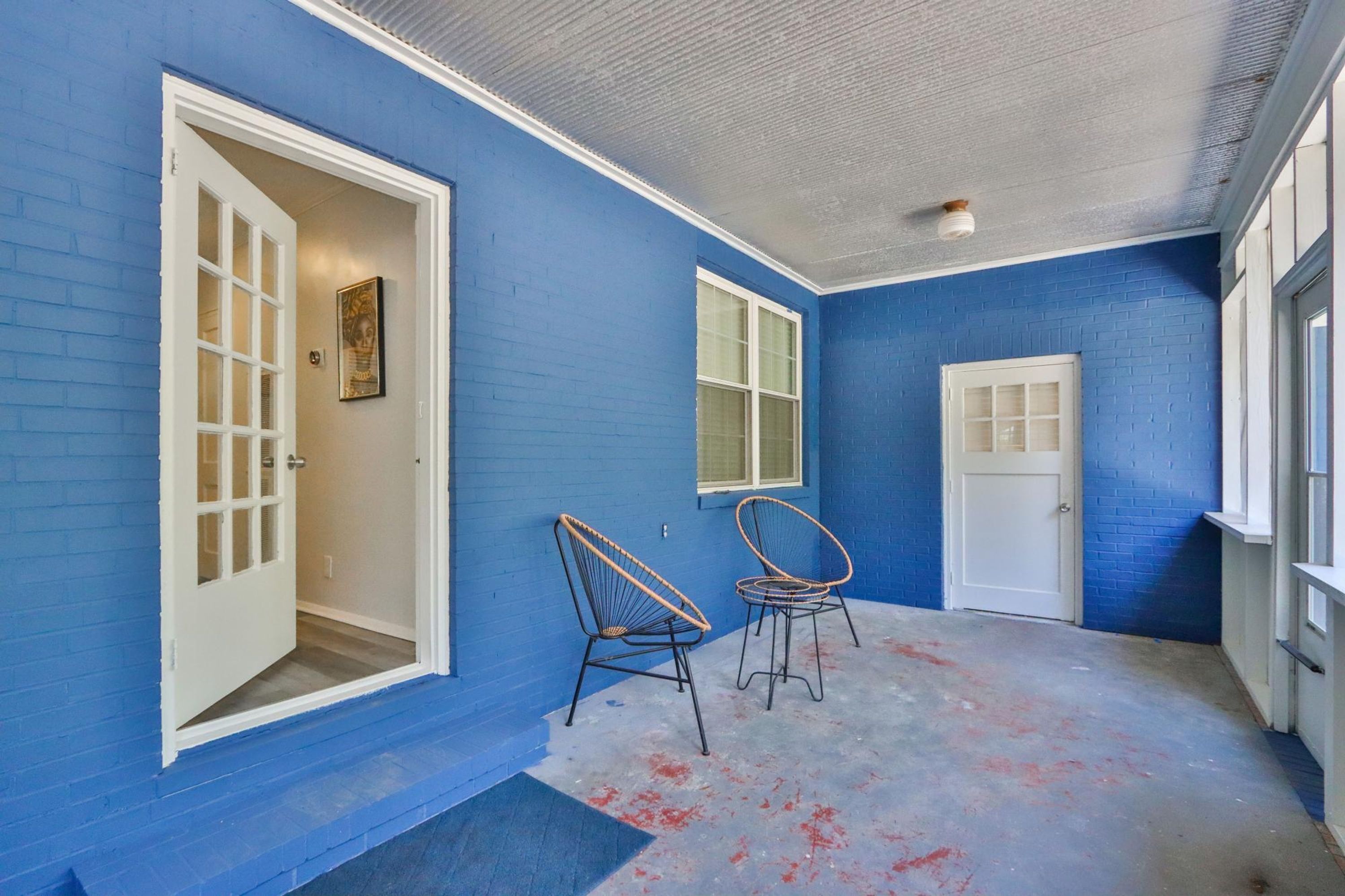 A room with blue walls, a white door, and two wicker chairs.