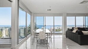 Enjoy a panoramic ocean view from the spacious living area with a dining table and comfortable seating.