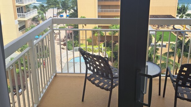 A balcony with a view of the ocean, a pool, and a building with balconies. - Beautiful 1 bedroom condo on the beach in Pompano Beach (Pompano Beach)
