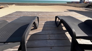 A wooden deck with two black lounge chairs facing a sandy beach and the ocean. - Beachfront Villa on Andros Island, Bahamas (Andros Town)