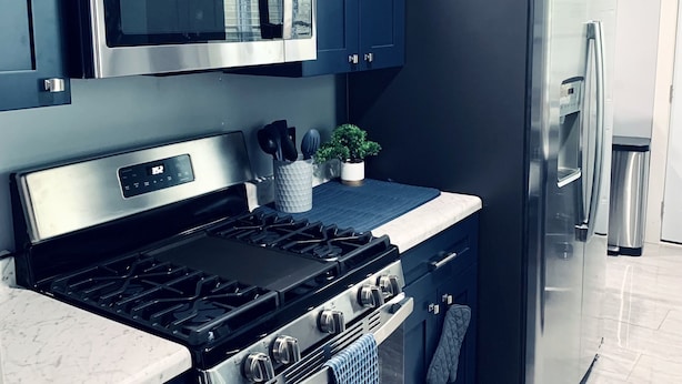 A modern kitchen with dark cabinets, stainless steel appliances, and a marble countertop. - Luxury 5 Bedroom Ranch Home: Walk to Notre Dame Campus / 2 Full Baths +Game Room (South Bend)