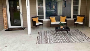 A covered porch with two chairs, a table, and a patterned rug. - Luxury 5 Bedroom Ranch Home: Walk to Notre Dame Campus / 2 Full Baths +Game Room (South Bend)