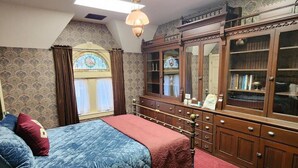 A bedroom with a bed, a dresser, a mirror, and a window with curtains. - Blue Room at the Feitshans House (Springfield)