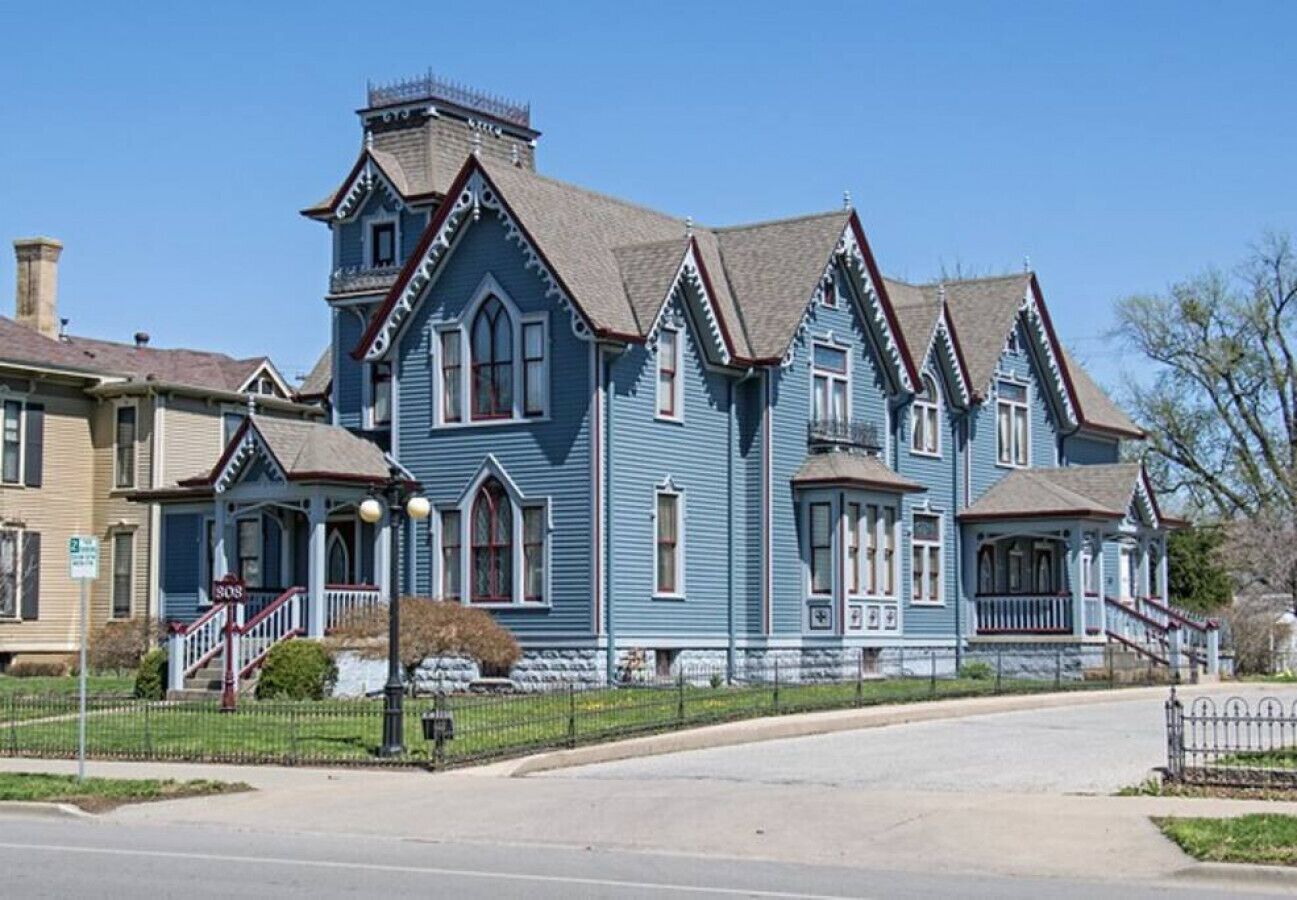 A large, historic blue house with multiple gabled roofs and a prominent front porch.
