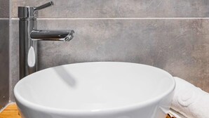 Een moderne badkamer met een ronde wastafel, een chromen kraan en een ronde spiegel erboven.