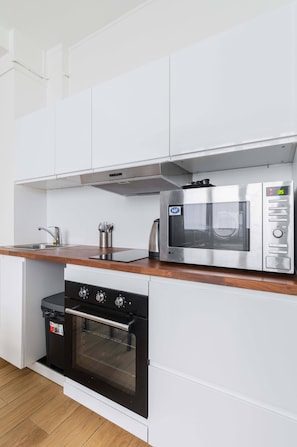 Una cocina compacta con microondas, horno y pileta.