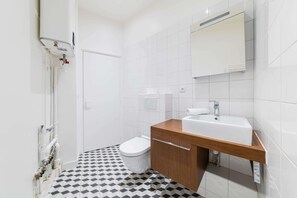 Casa de banho moderna com sanita, lavatório e chuveiro.