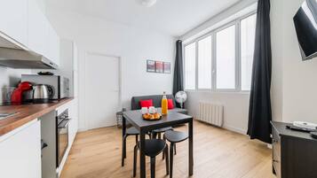 Een moderne keuken met een eethoek, een bank en een groot raam met gordijnen.
