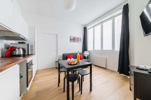 Una cocina moderna con comedor, sofá y un amplio ventanal con cortinas.